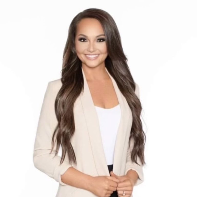 Smiling woman in a light blazer with long hair, posing confidently.
