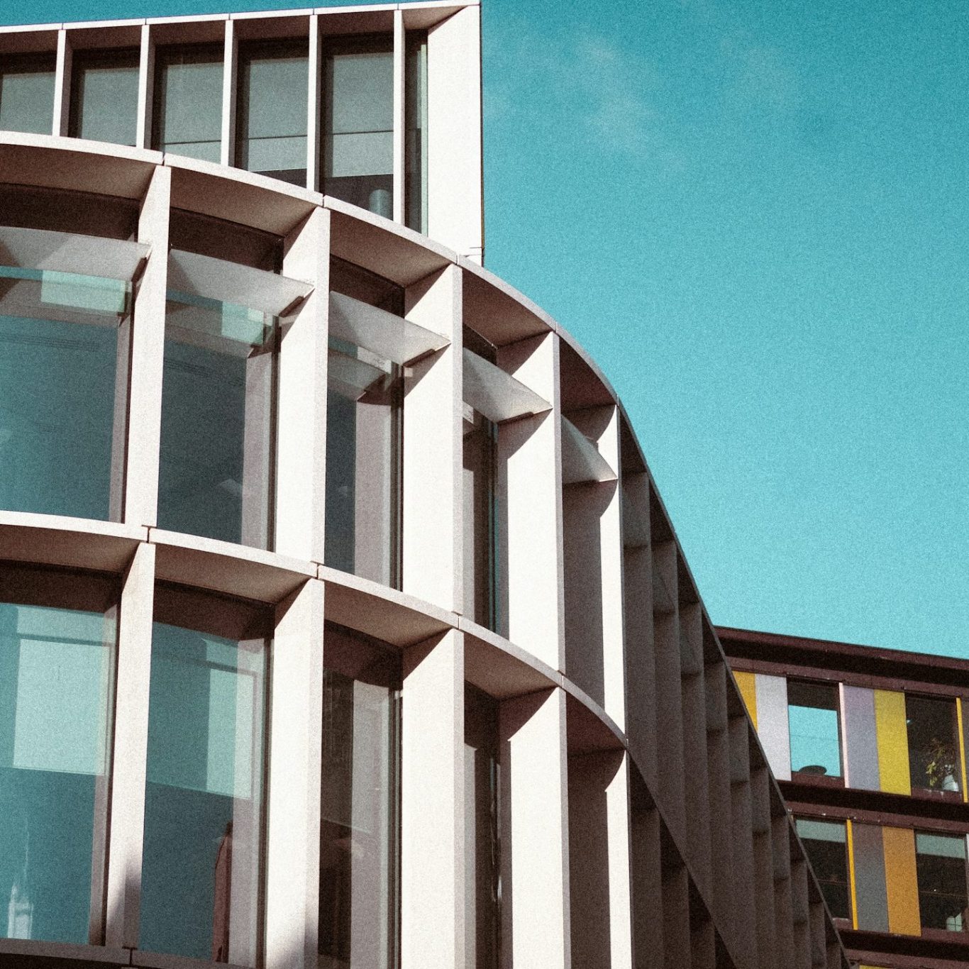 Modern building with curved architecture and large windows against a clear blue sky.