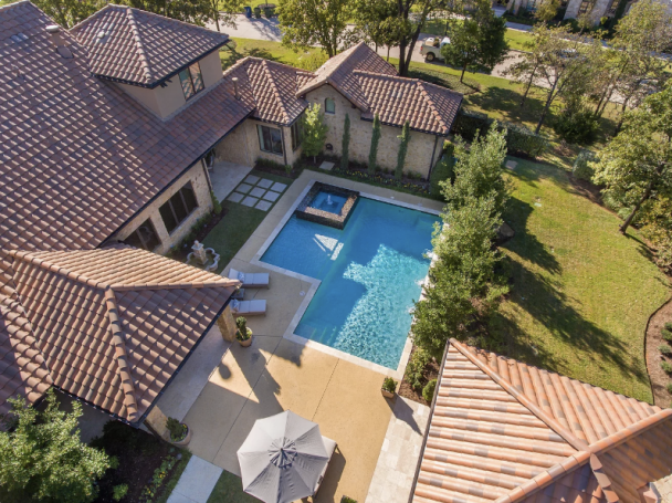 Aerial view of a luxurious home with a pool and surrounding greenery.