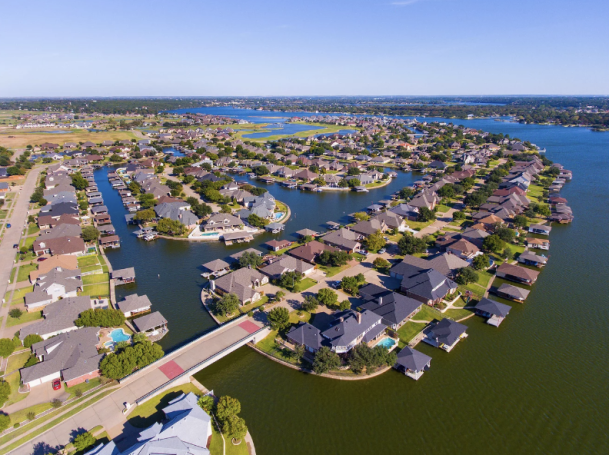 Aerial view of a circular waterfront community with houses along winding waterways.