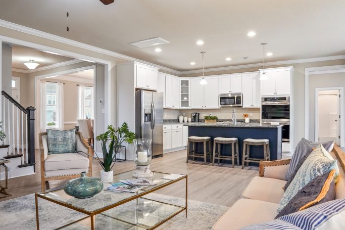Modern kitchen and living area with light decor, island seating, and natural light.