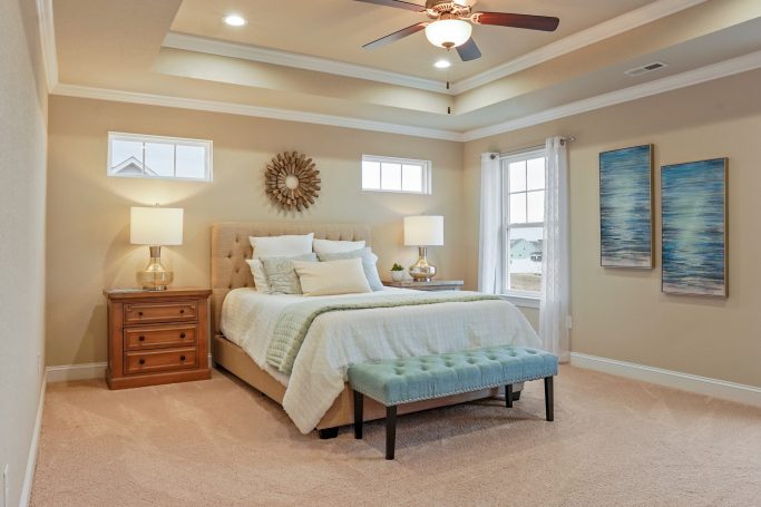 Cozy bedroom with a bed, nightstands, lamp, artwork, and a decorative bench.